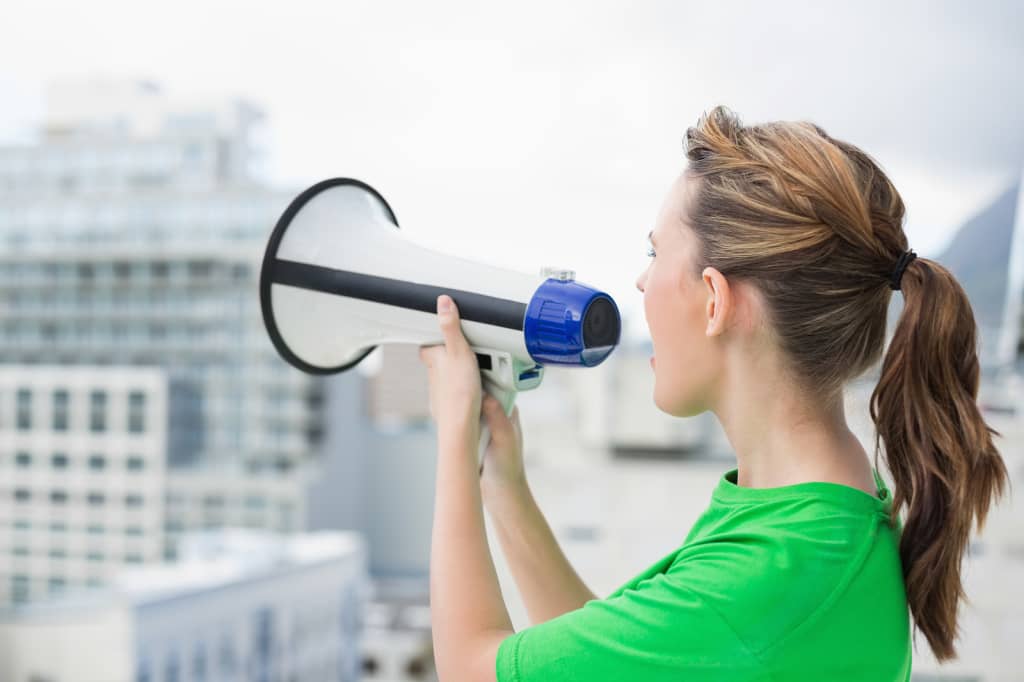 Side view of woman using and screaming in megaphone