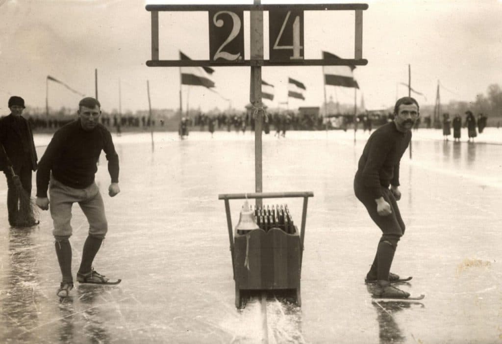 Vintage photo of two ice skaters lining up to race and representing the contest between leading and managing