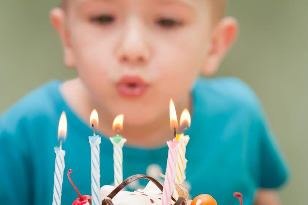 Boy blowing out candles at his own birthday party displays principled behavior.